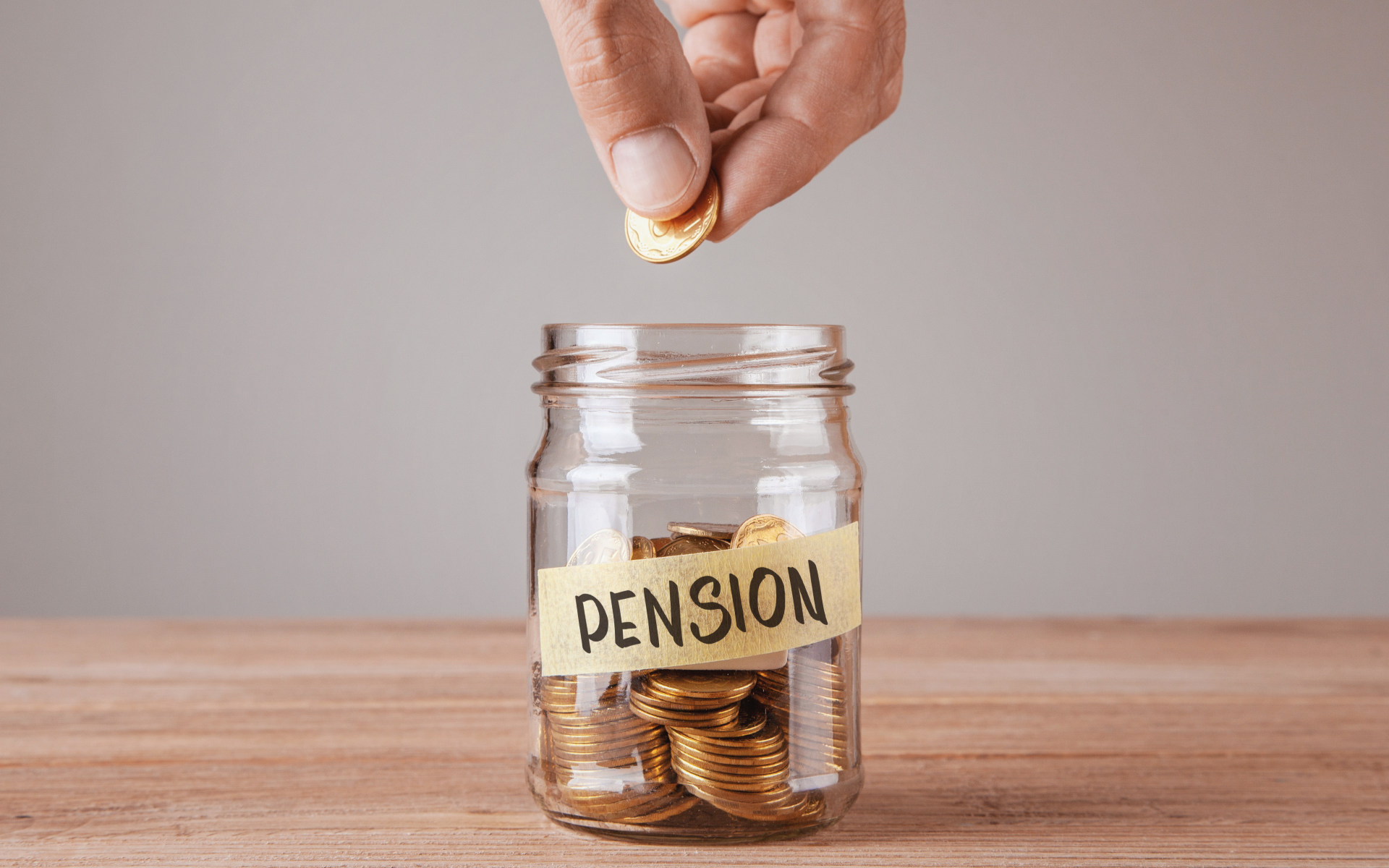 A hand drops coins into a glass jar