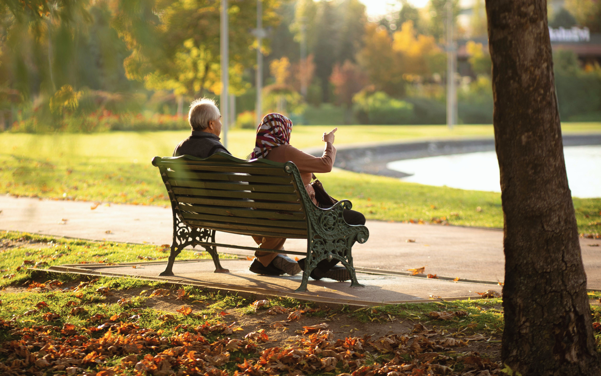 A retired couple sits on a park bench