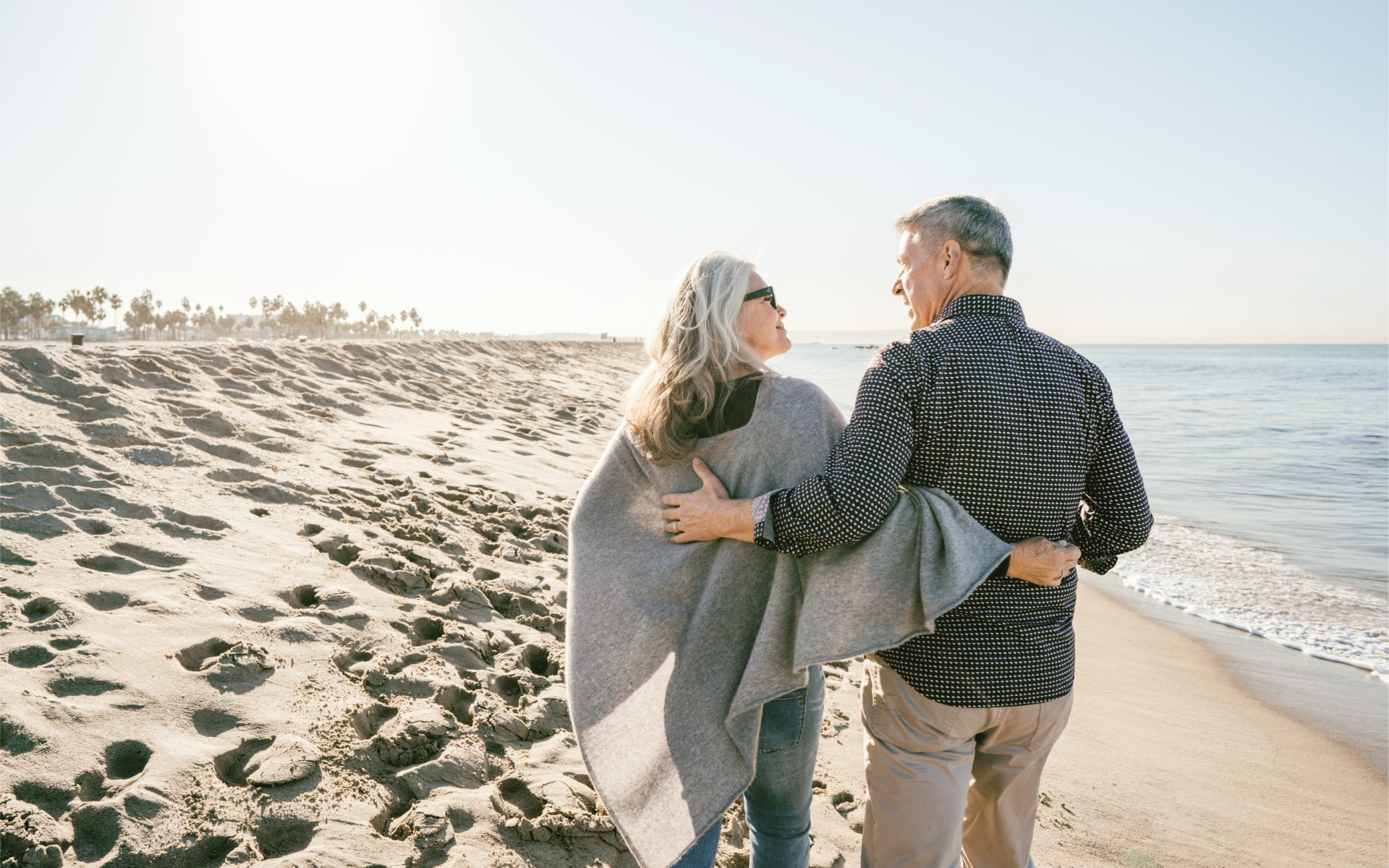 A couple walks on the beach during retirement