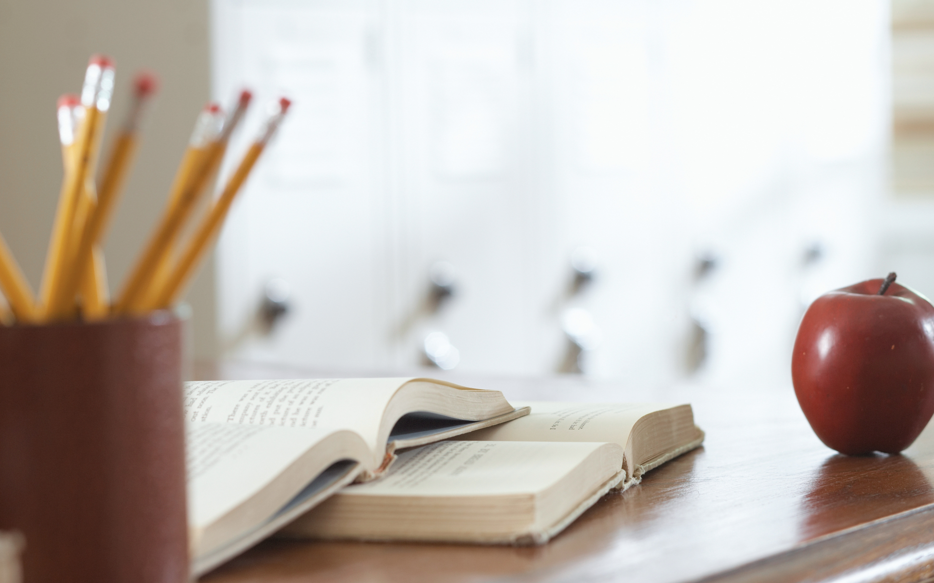 Pencils, books, and an apple on a teacher's desk