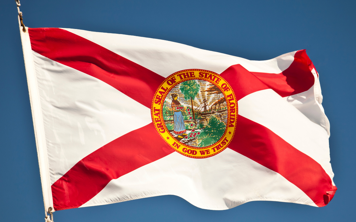 The flag of the State of Florida, featuring a white background with a red saltire and the Great Seal of the State of Florida in the center.