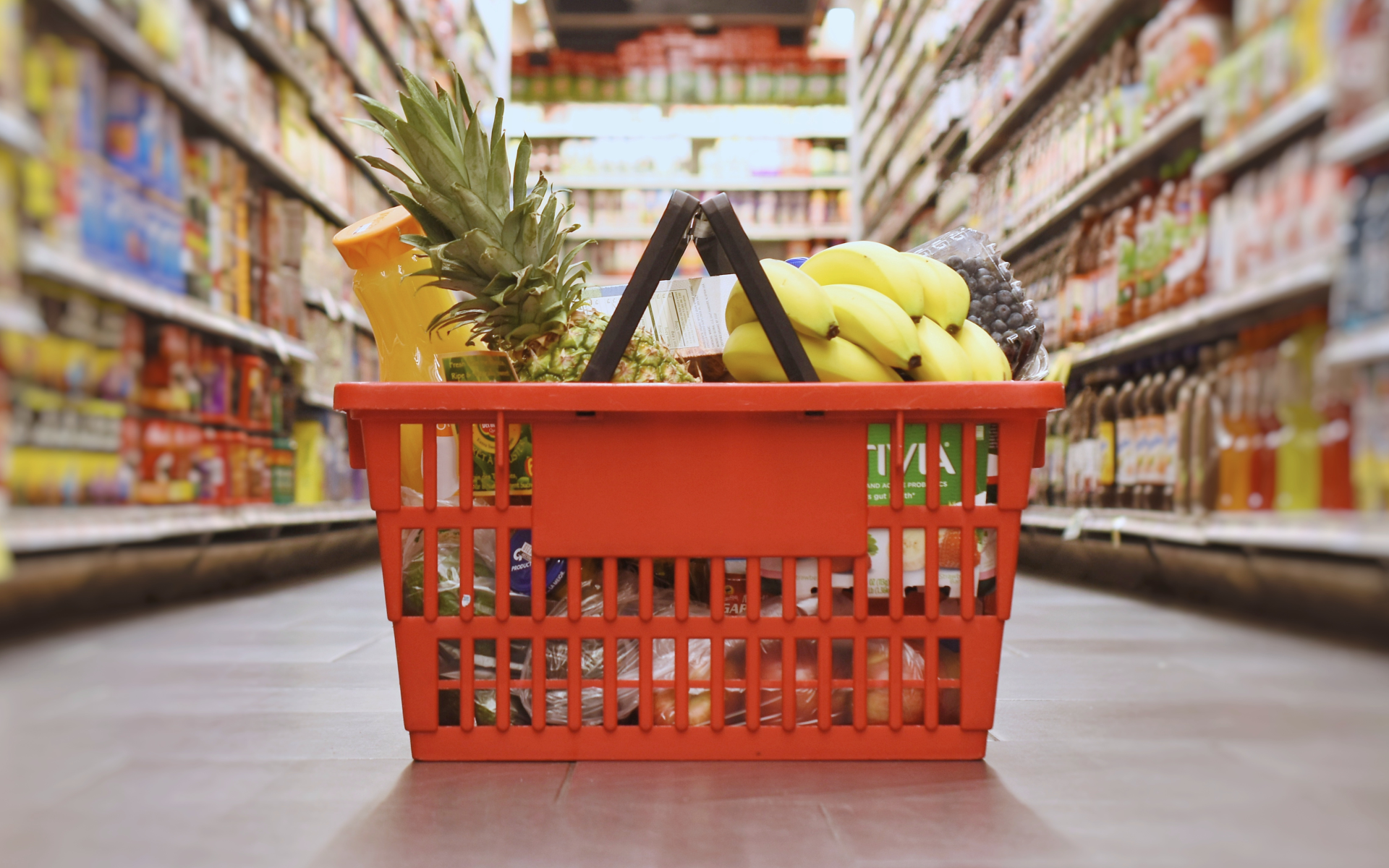 A basket filled with groceries sits on the floor of a grocery store.